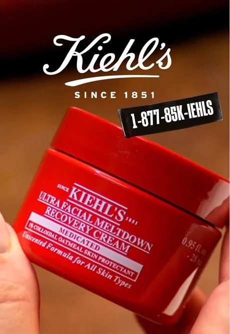 A person holding a red jar of Kiehl's Ultra Facial Meltdown Recovery Cream with a black label showing a phone number, with Kiehl's logo and branding above.