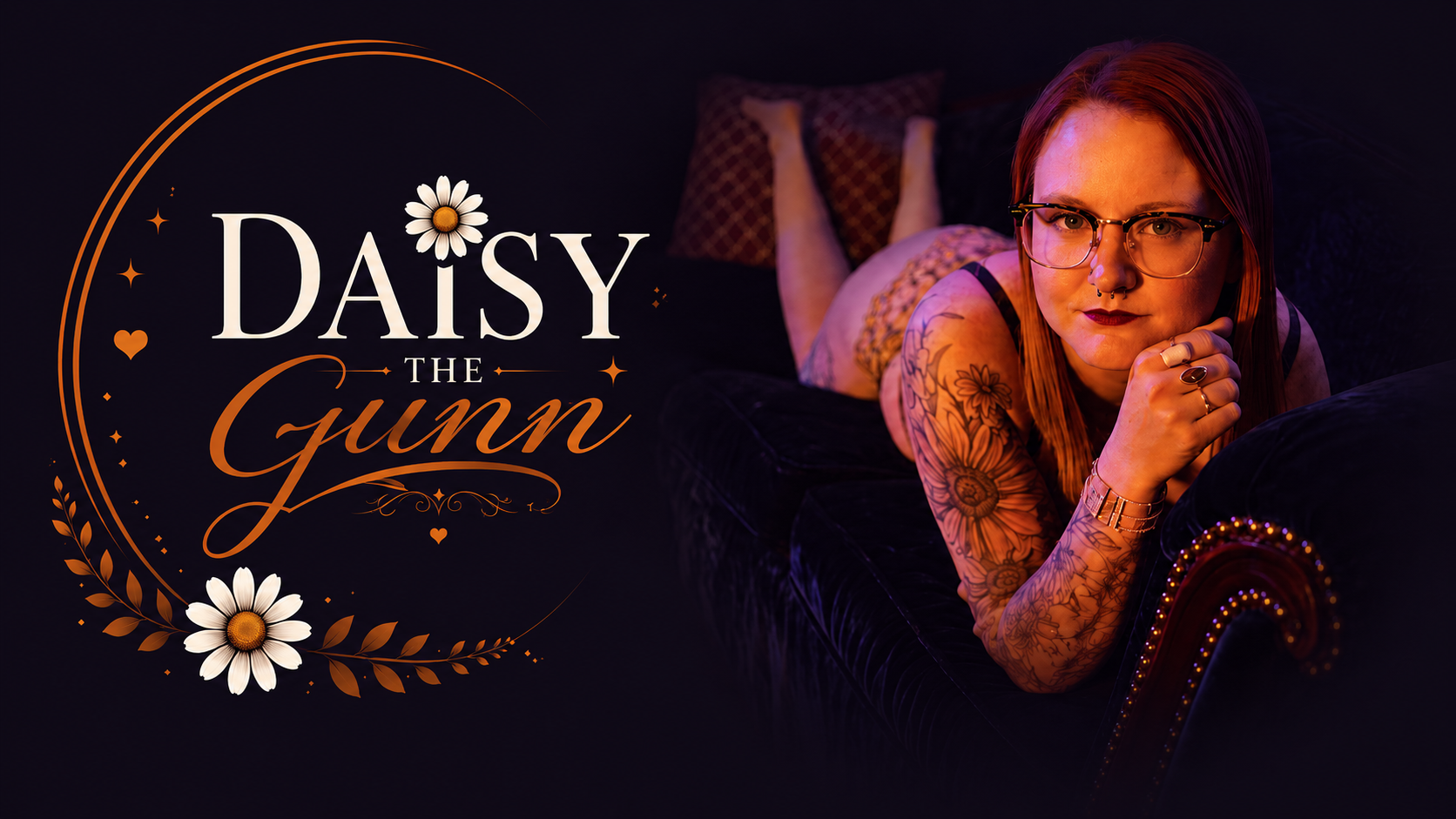 A woman with red hair, glasses, tattoos, and piercings relaxing on a dark velvet couch, resting her chin on her hand, with a thoughtful expression, in a dimly lit room with a dark background. The image features text that reads 'Daisy the Gunn' with decorative hearts, stars, and daisies.