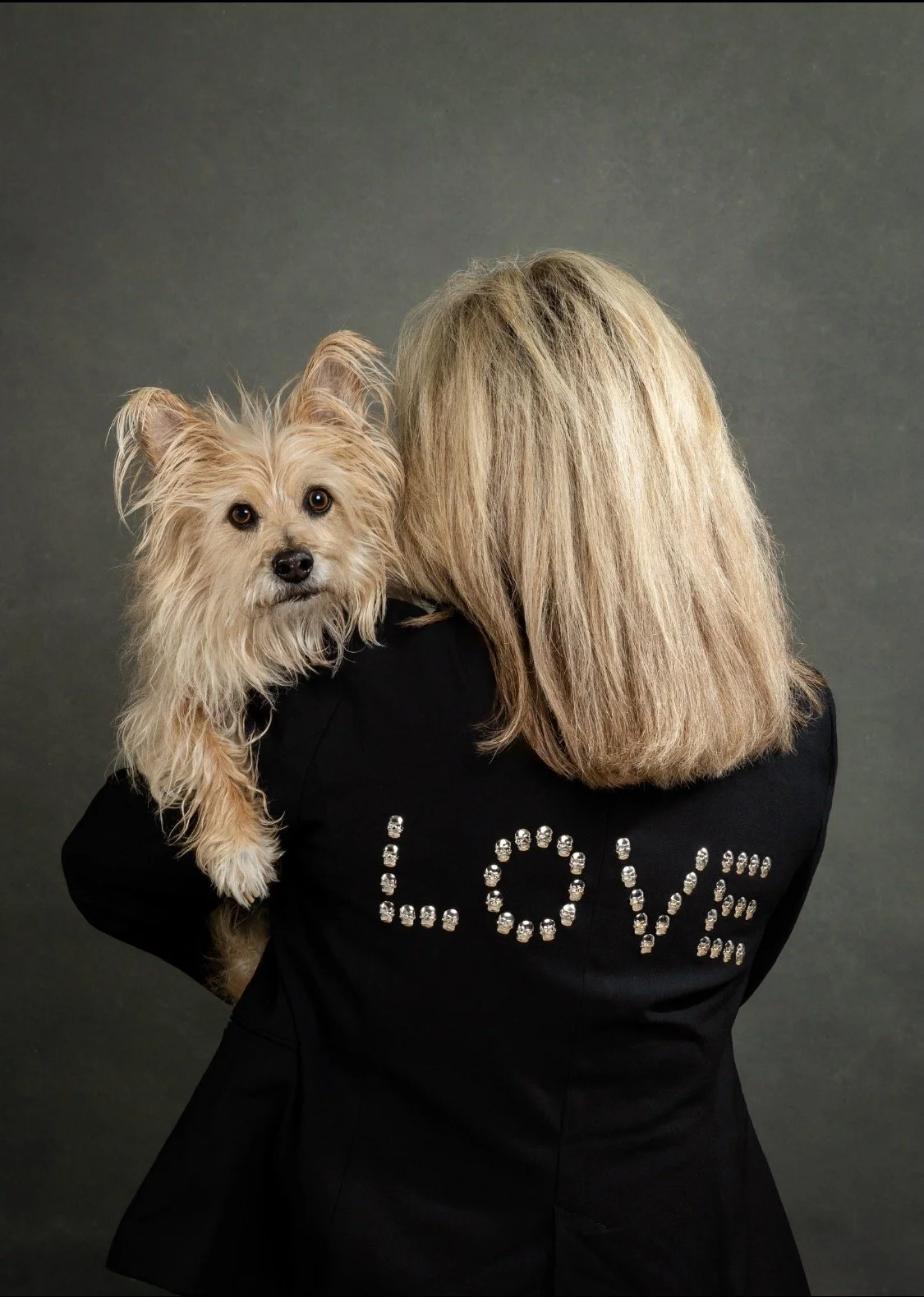 Vicki Ferguson holding her dog Gomez in a playful portrait.