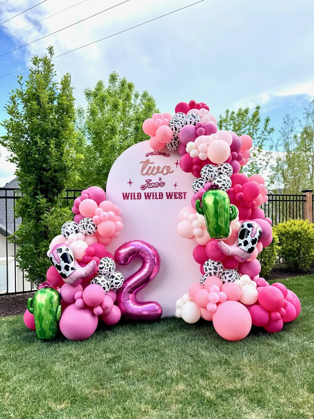 Pink birthday balloons surrounding a personalized garden party backdrop
