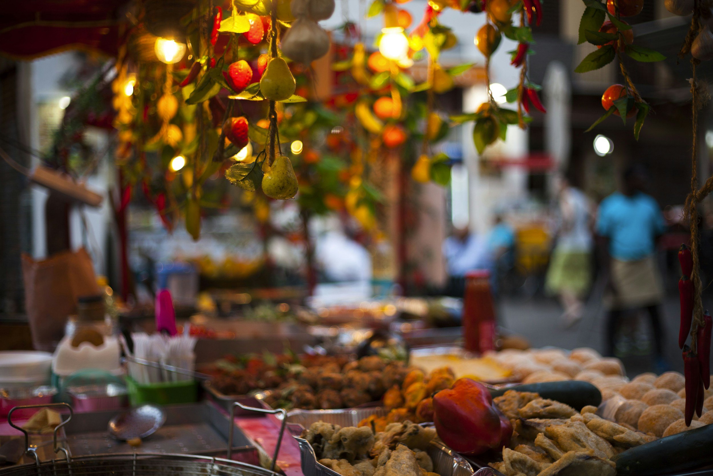 Bunte Marktstände mit Obst, Gemüse und Kunsthandwerk bei einem nächtlichen Markt, beleuchtet mit warmem Licht.