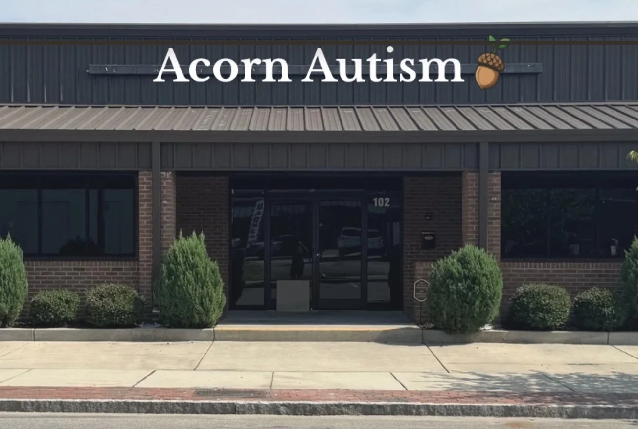 Building with sign that reads 'Acorn Autism' and acorn and leaf logo, brick exterior with shrubs in front