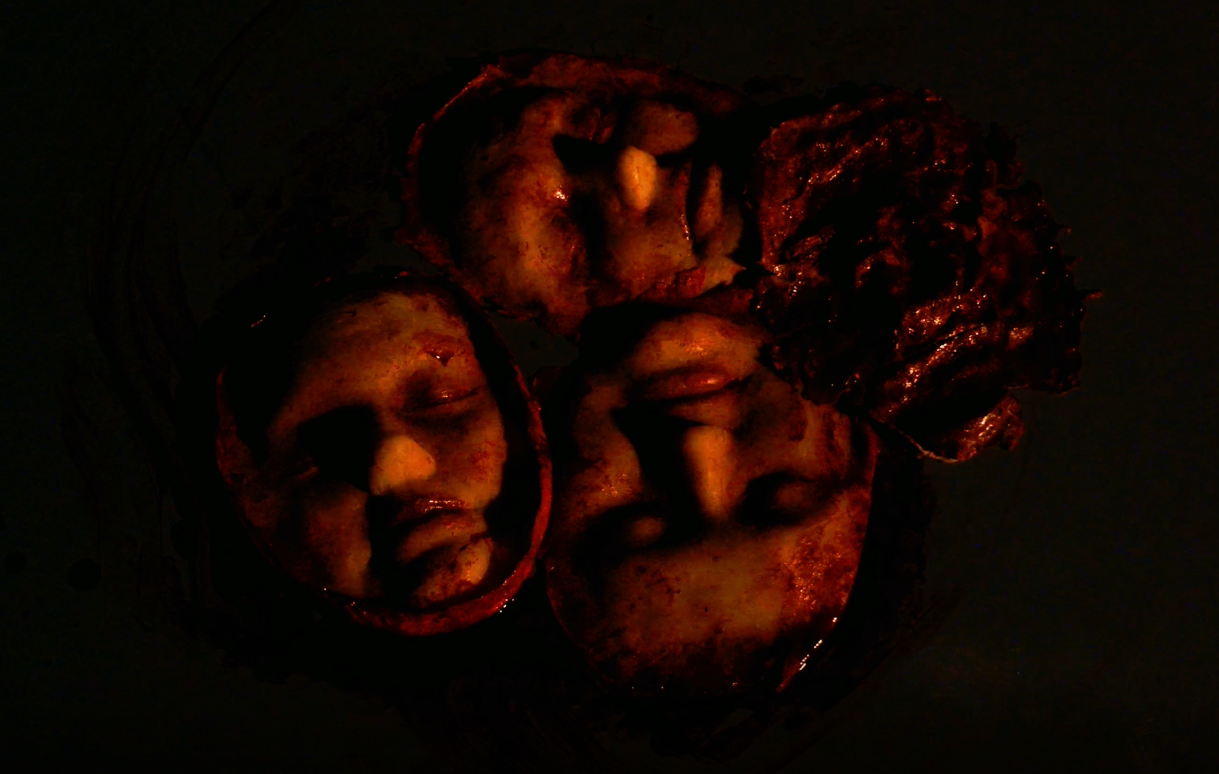 Close-up of three human faces severed in a bloody pile