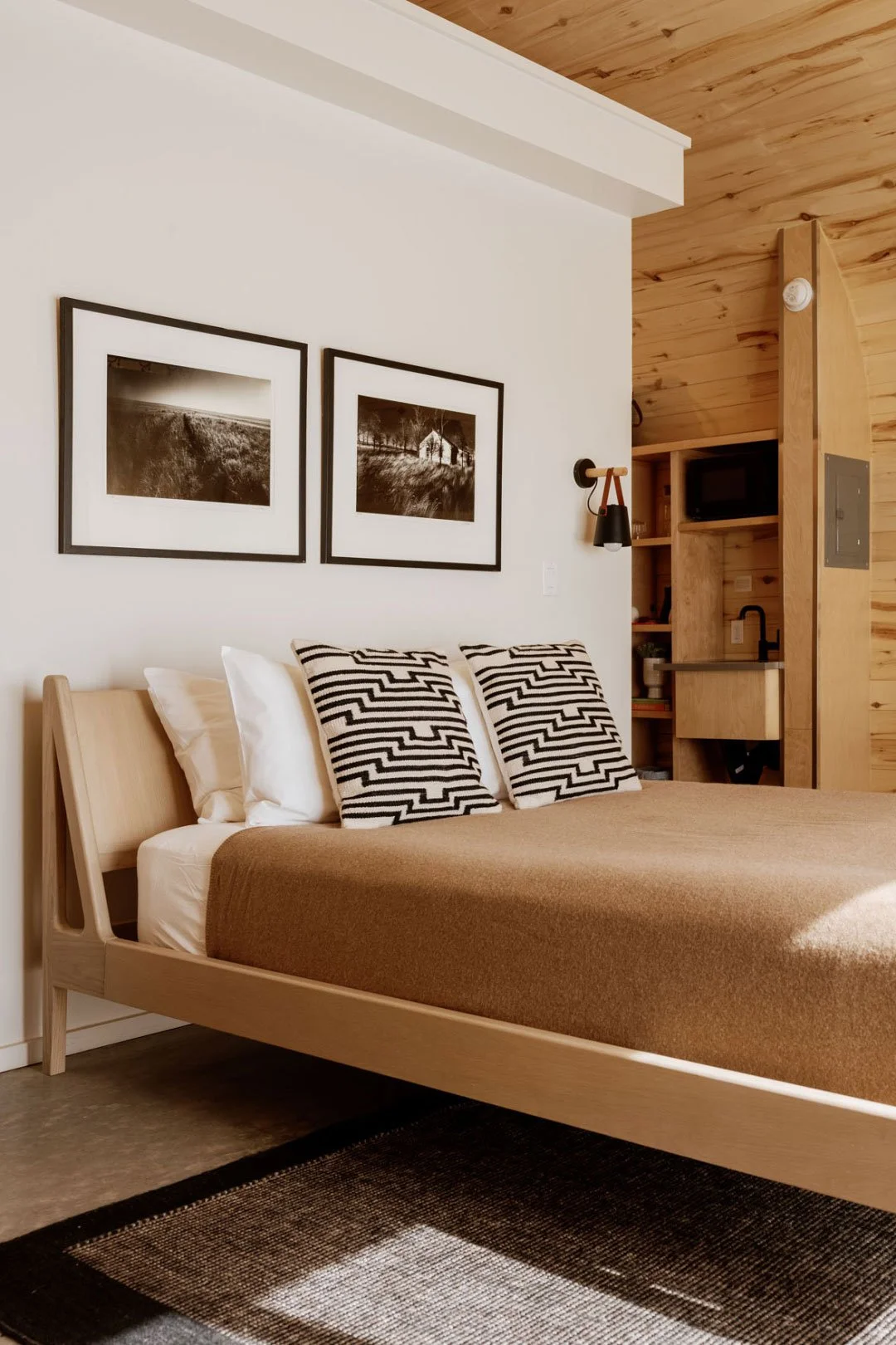 A queen size bed with neutral bedding and surround decor.