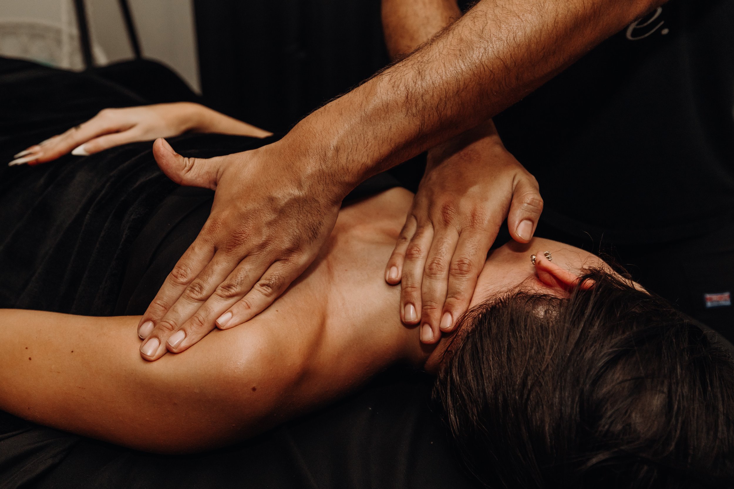 Close-up of a person lying face down receiving a massage, with hands massaging their back.