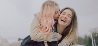 Two women hugging and smiling outdoors