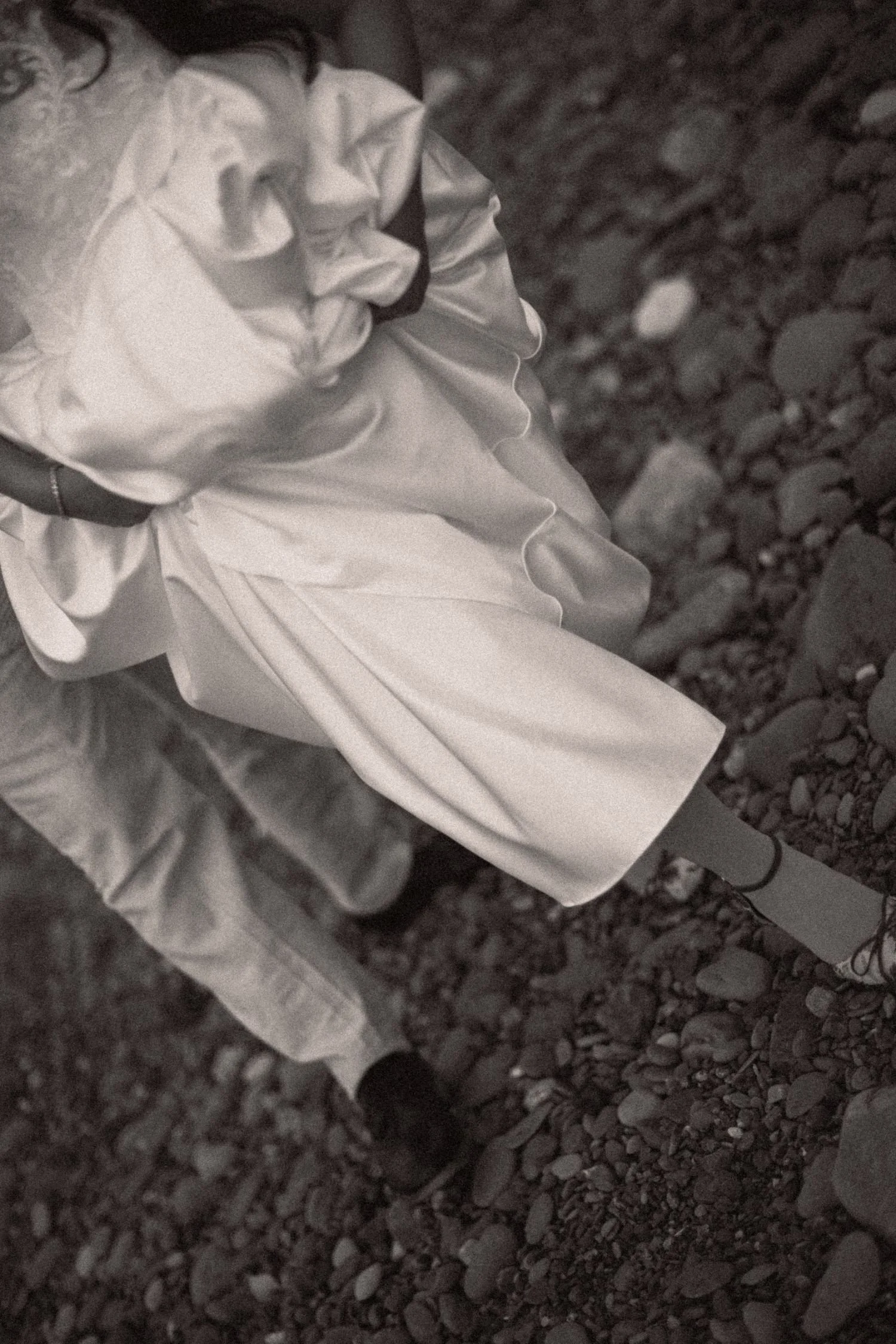 A girl wearing a dress and shoes standing on a rocky surface.