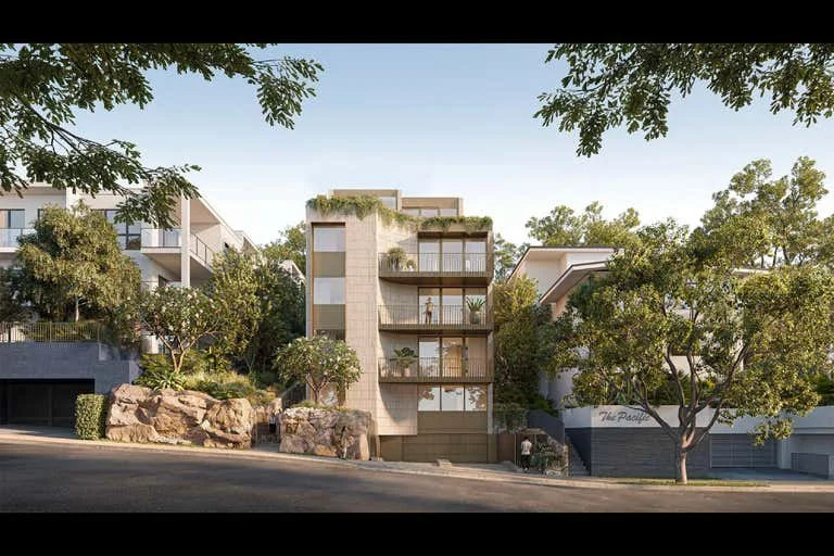 Modern multi-story residential building with large glass windows and balconies, surrounded by trees and greenery, with rocks and a driveway in front.