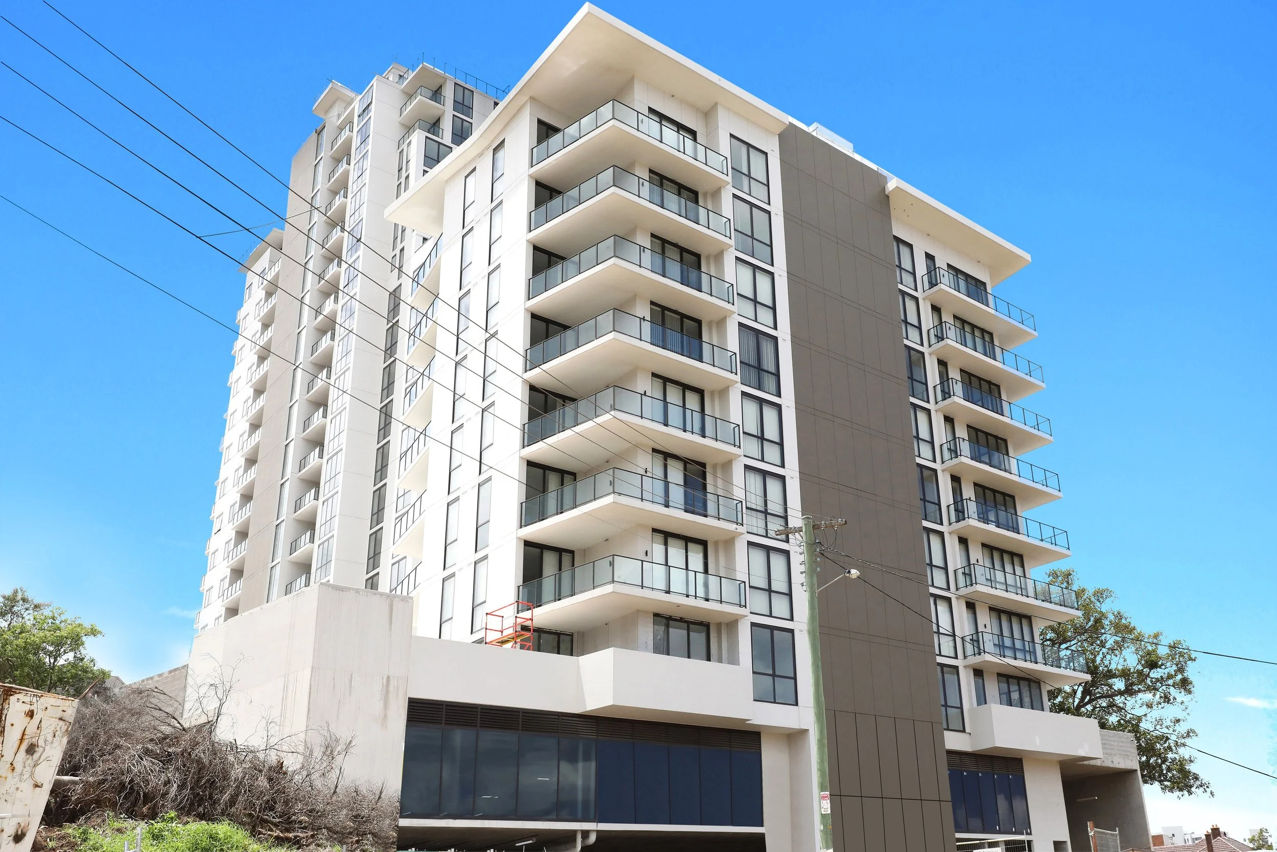 Modern multi-story apartment building with balconies under a clear blue sky.