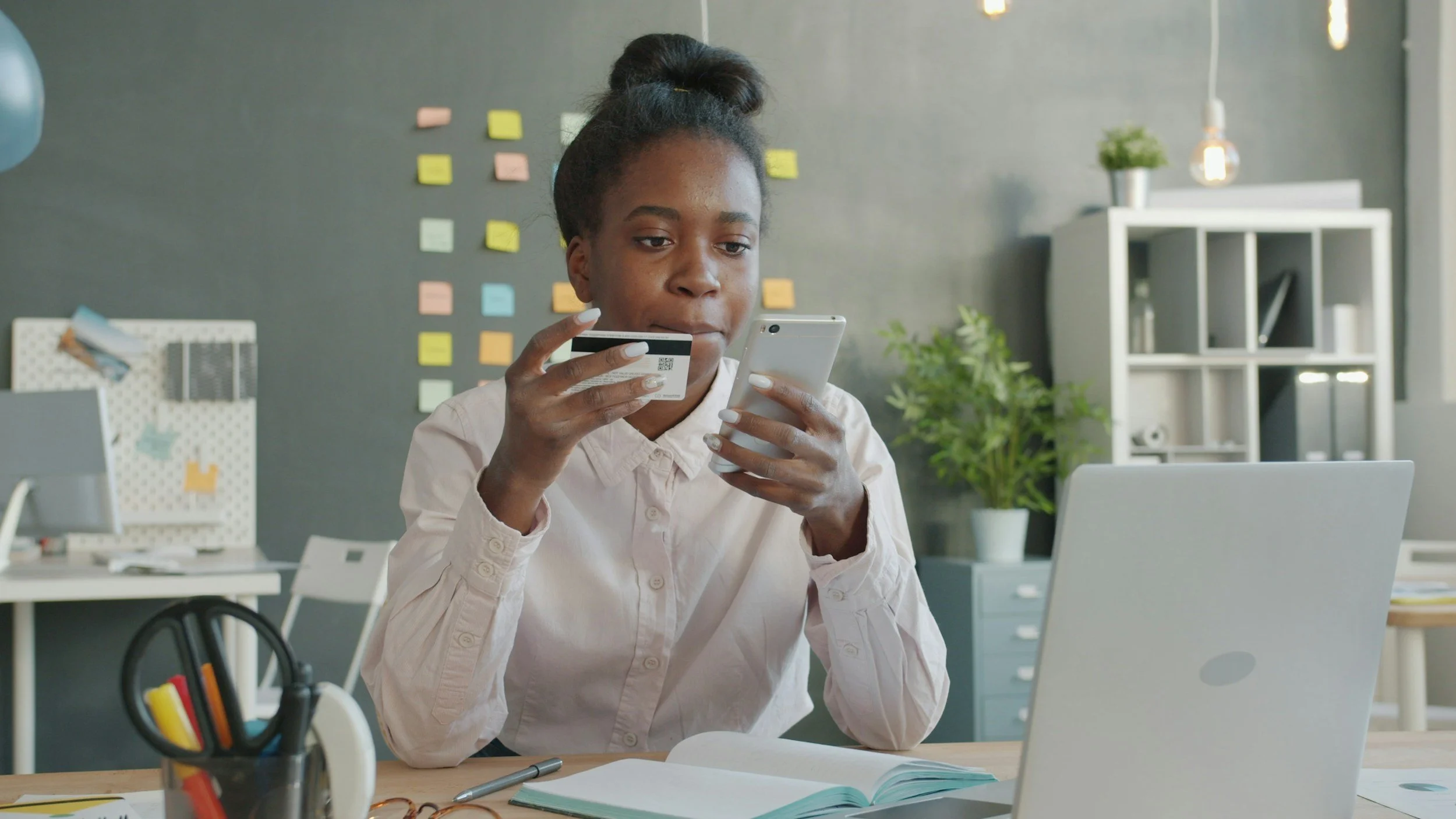 Woman sitting at a desk with a laptop, taking a thoughtful pause during her workday, reflecting work-related stress and the pressure of perfectionism.