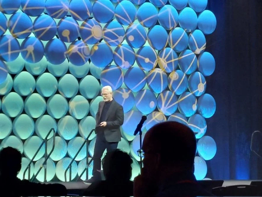 Perry Carpenter on-stage. Blue background.