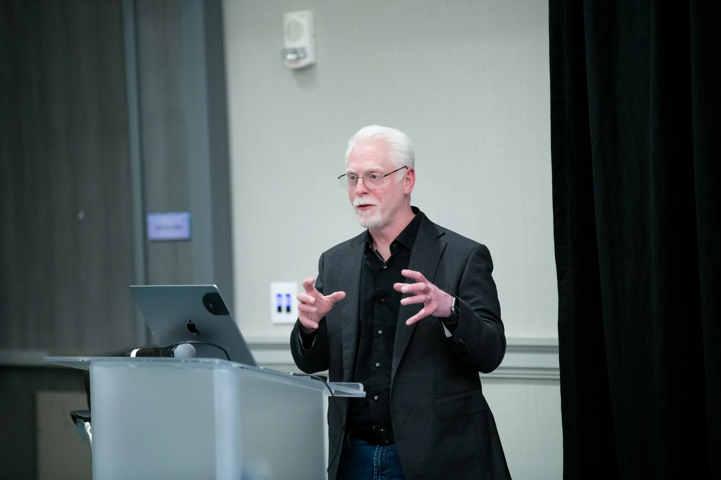 Perry Carpenter standing behind a podium with a laptop and a microphone.