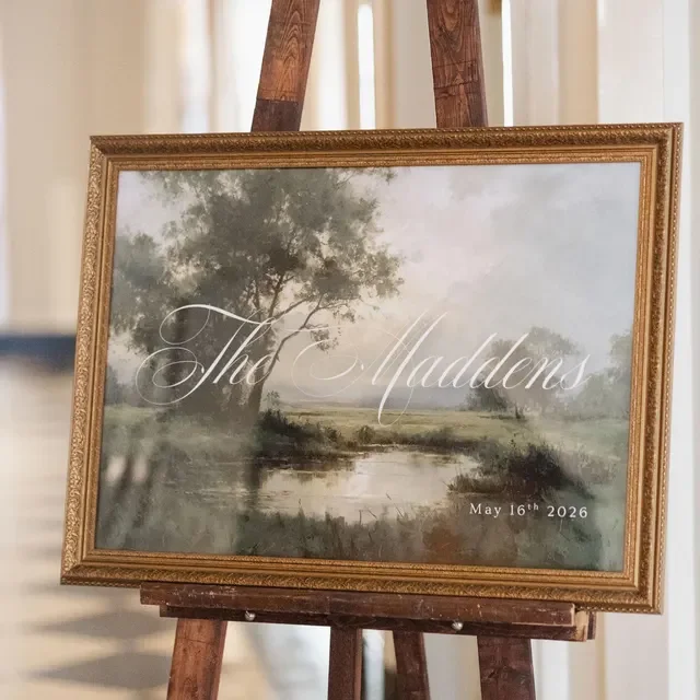 Framed wedding sign featuring a landscape painting of trees and a pond, displaying the names The Maddens and the date May 16th, 2026. Handmade by January Swift Studio.