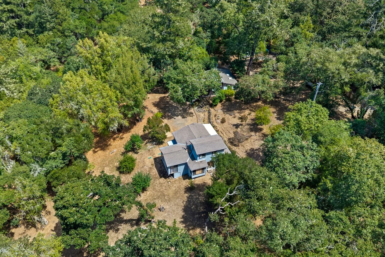 An aerial view of a house surrounded by trees in a wooded area.