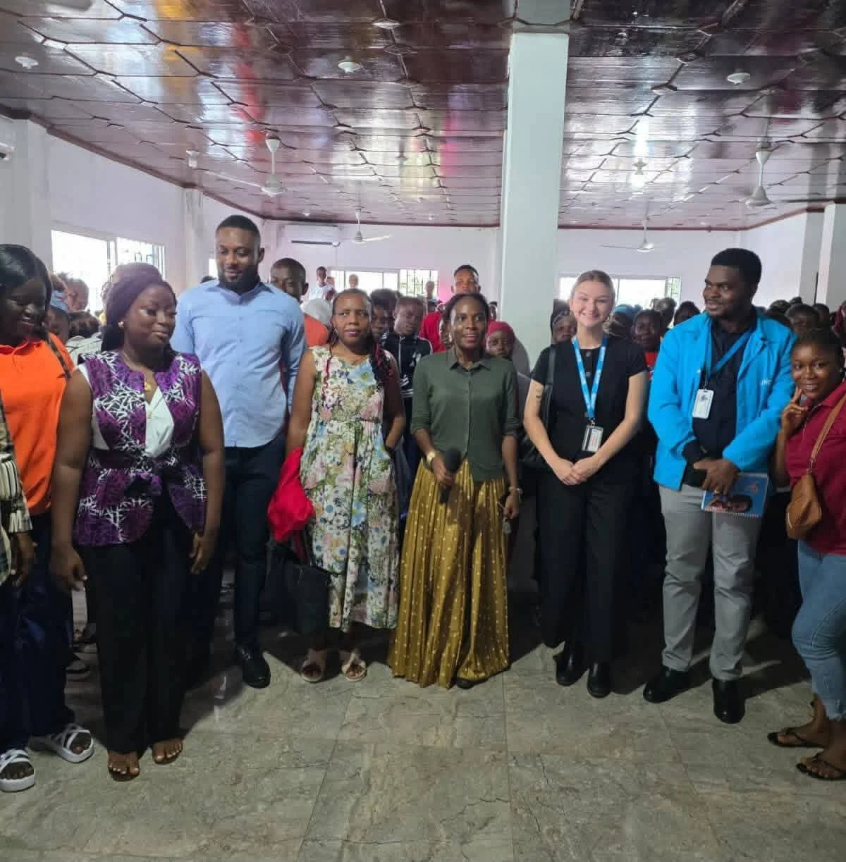 A diverse group of people standing together in a spacious indoor setting, smiling and posing for the photo, with some wearing conference badges.