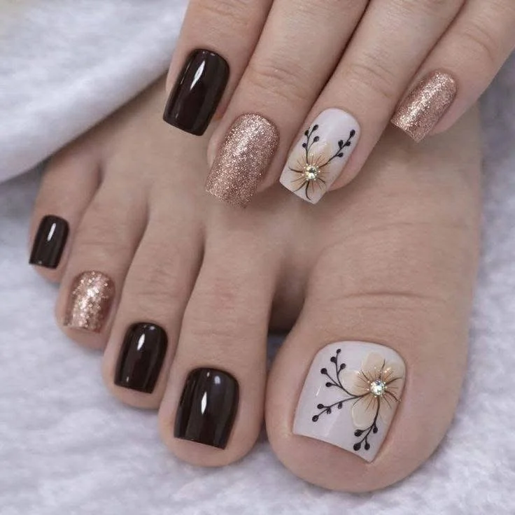 Pedicure with dark brown, glitter gold, and floral nail art on toenails.