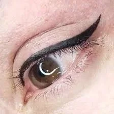 Close-up of a human eye with black eyeliner and mascara, showing eyelashes and part of the eyelid