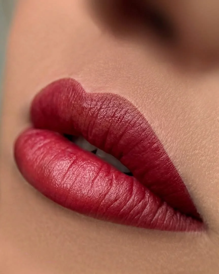 Close-up of lips wearing dark red lipstick, showing detailed texture and smooth skin.