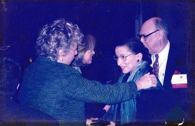 Four people in formal attire engaged in conversation at a social gathering or event.