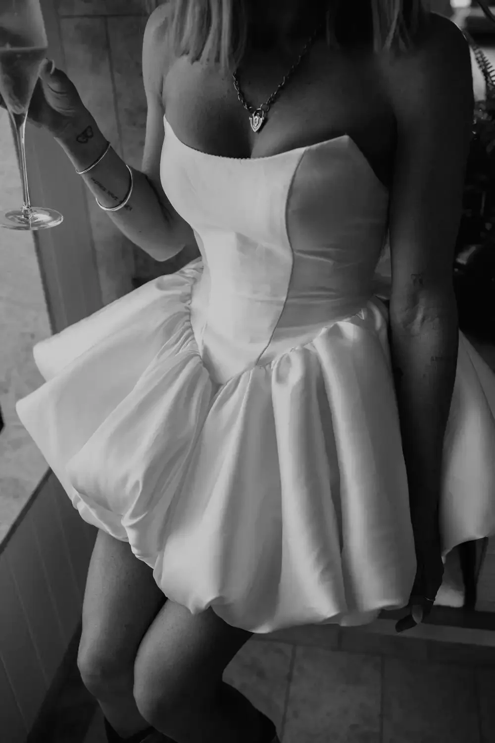 A woman in a strapless dress holding a champagne glass at a celebration or event.