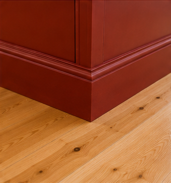 Close-up of a wooden furniture piece with a reddish finish, placed on a light hardwood floor.