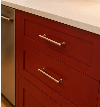 Close-up of red kitchen cabinet drawers with gold handles and a white countertop.