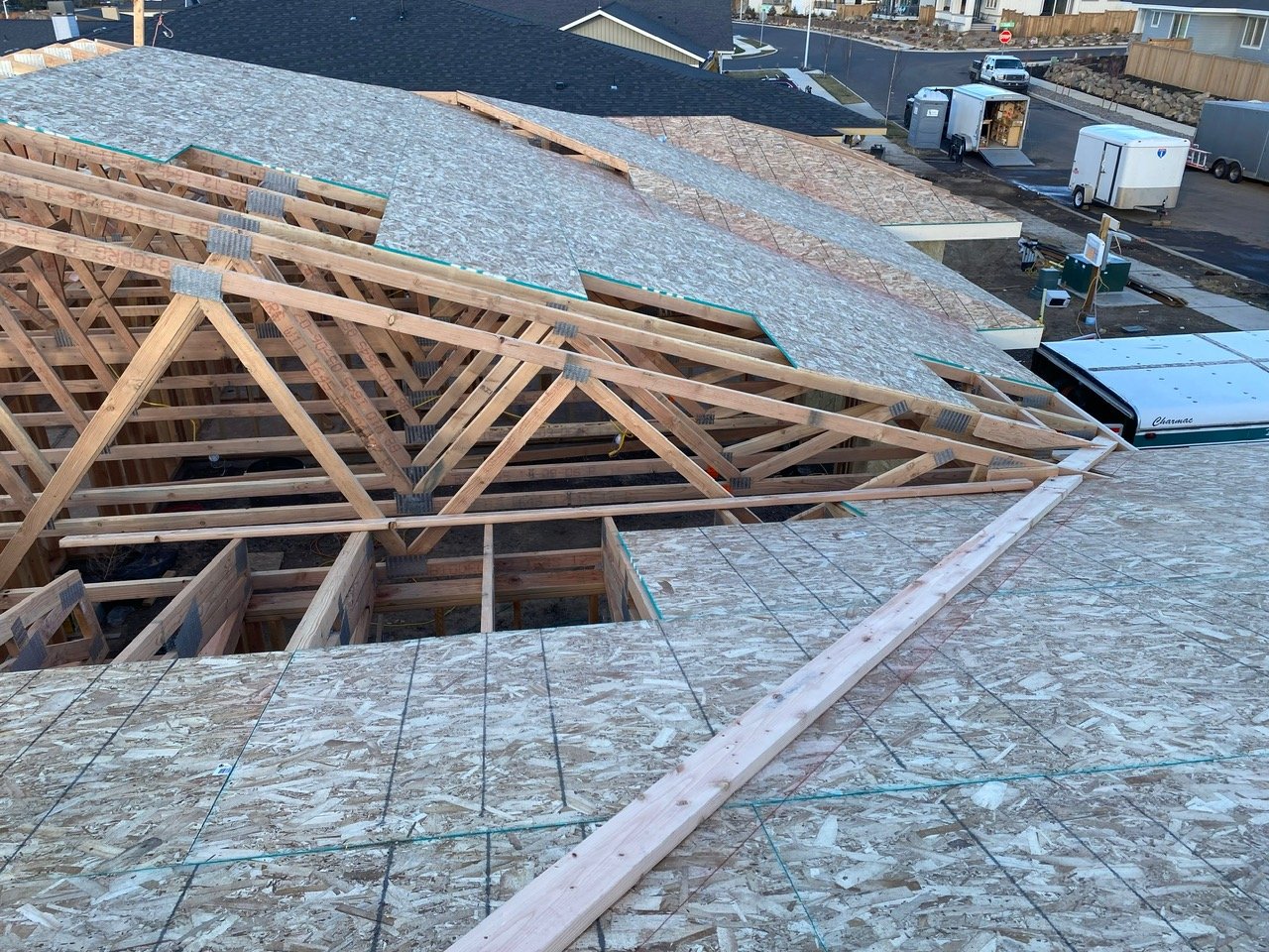 Building under construction with wooden roof trusses and plywood sheathing.
