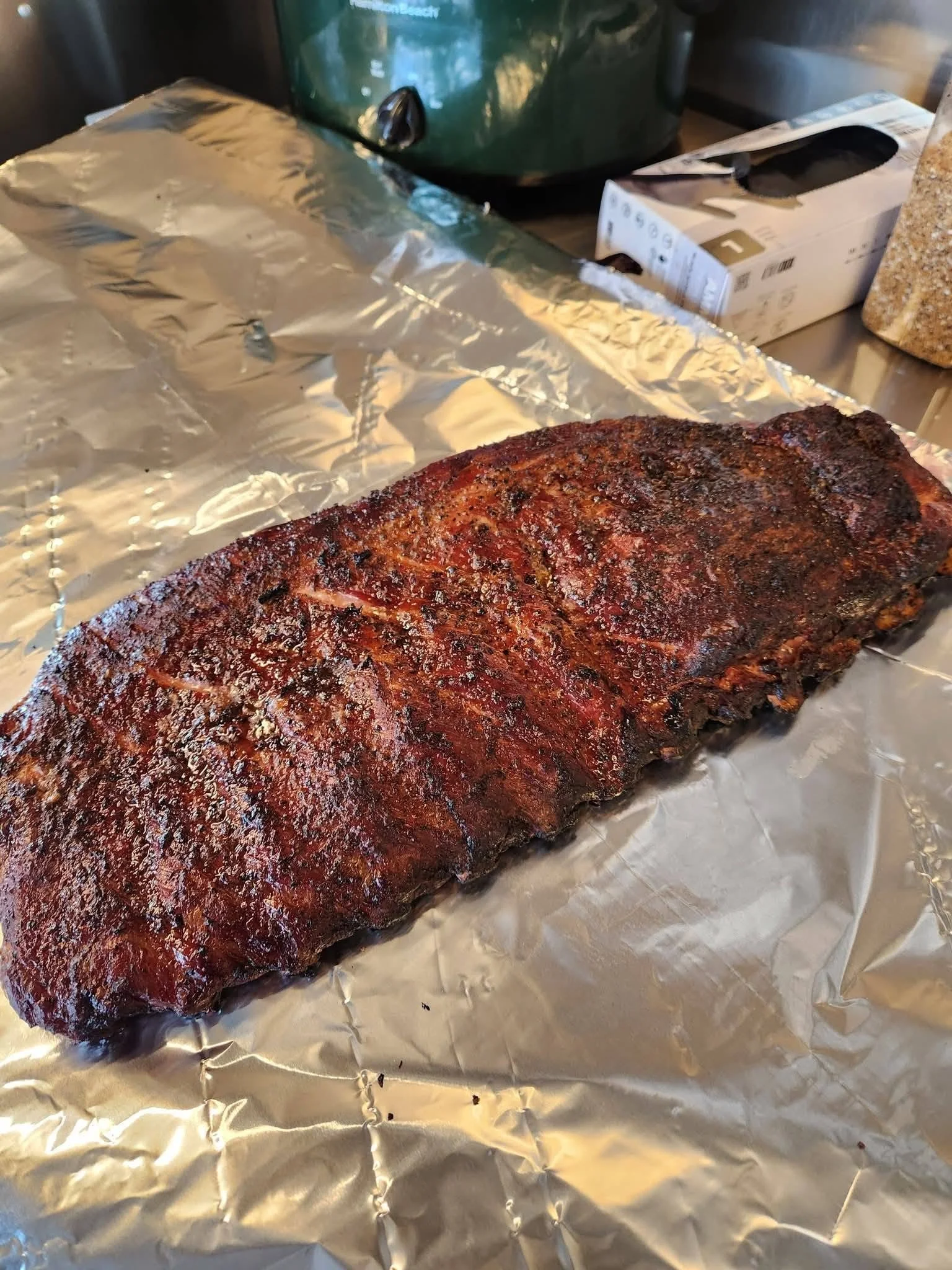 A large piece of cooked barbecue brisket resting on aluminum foil.