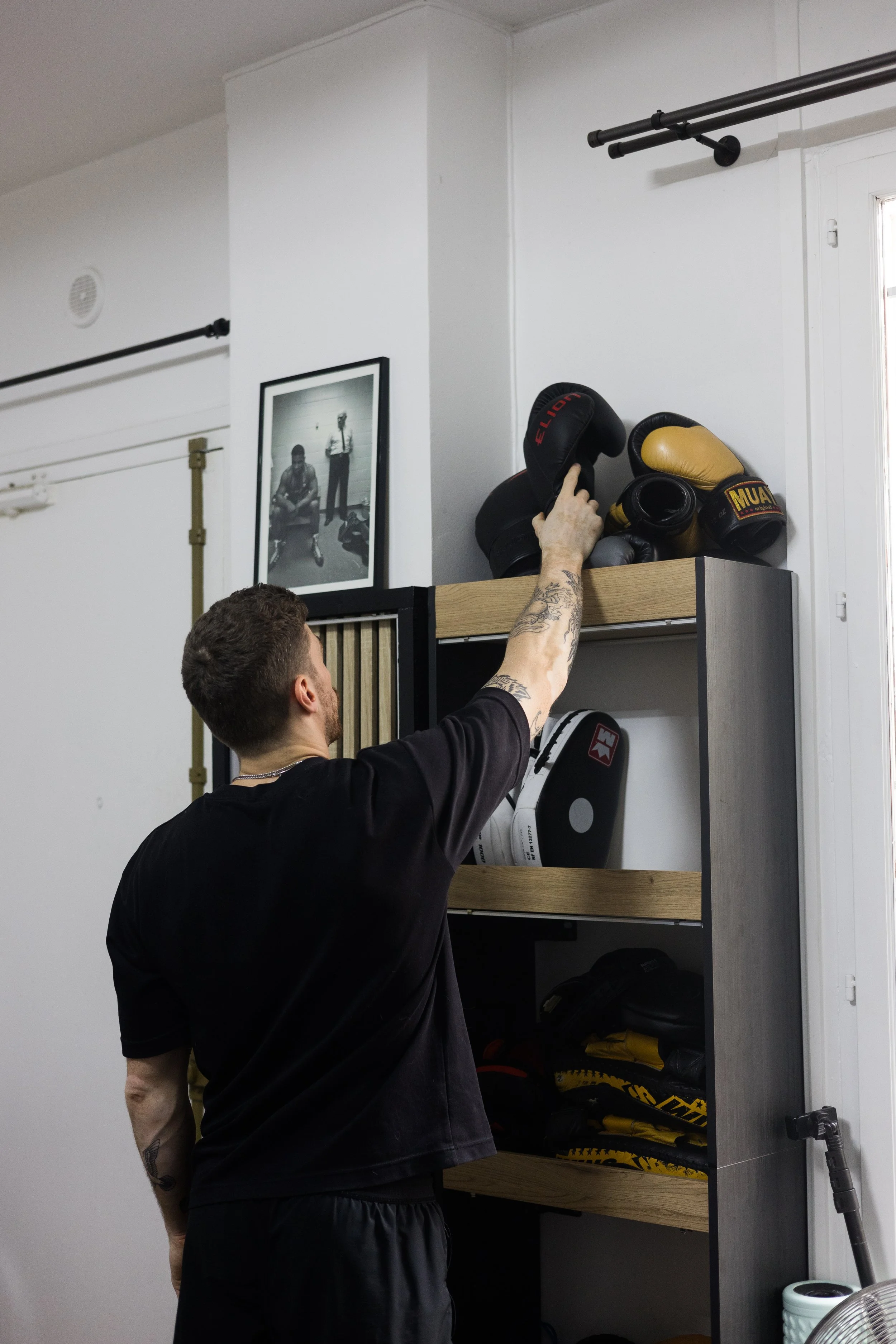 Le coach range une paire de gants de boxe sur une étagère dans le studio de coaching.