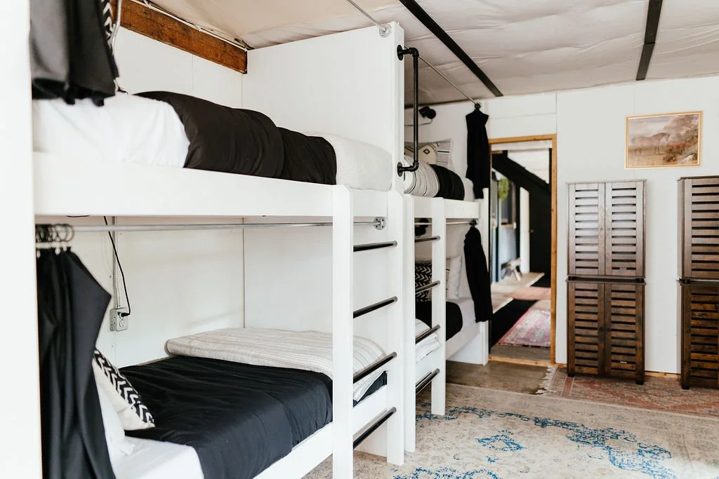 Bunk beds in a cozy room with wooden accents, dark curtains, and a patterned rug.