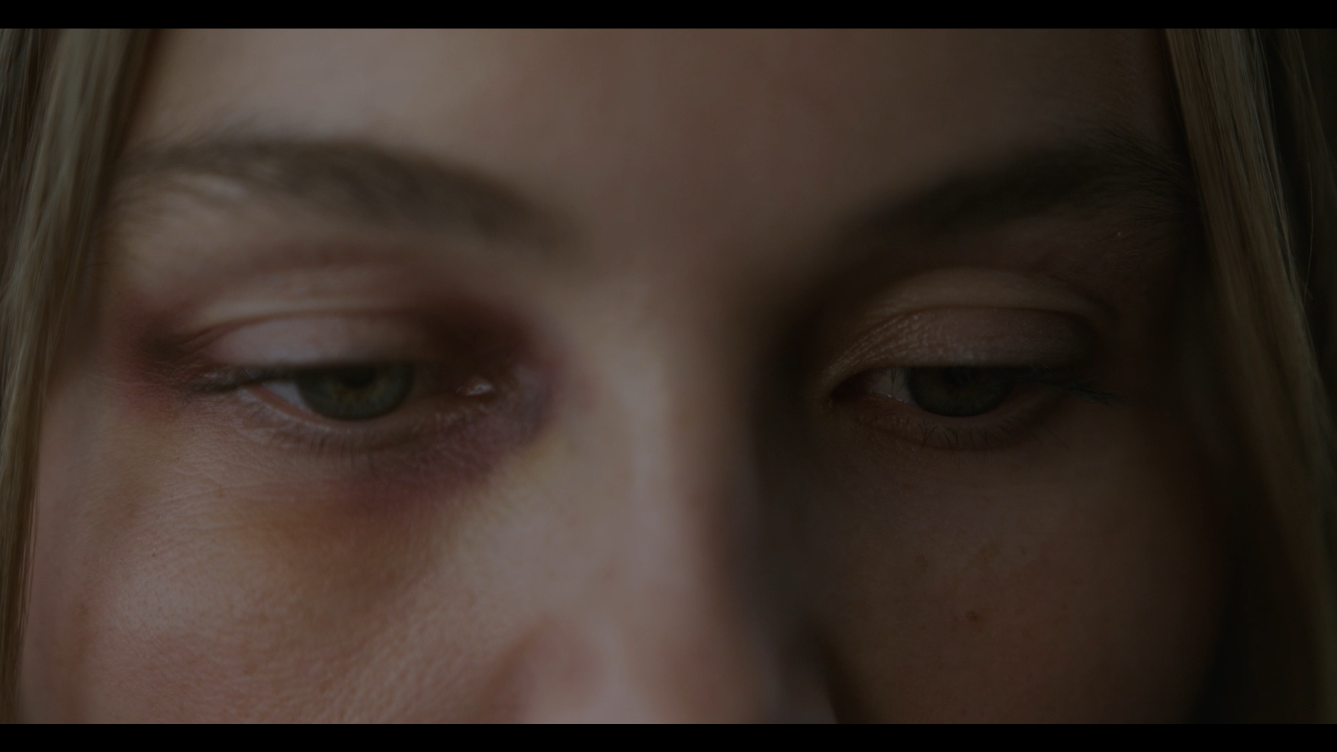 Close-up of a person's face with only the eyes and part of the forehead visible, eyes partially closed with a neutral expression.