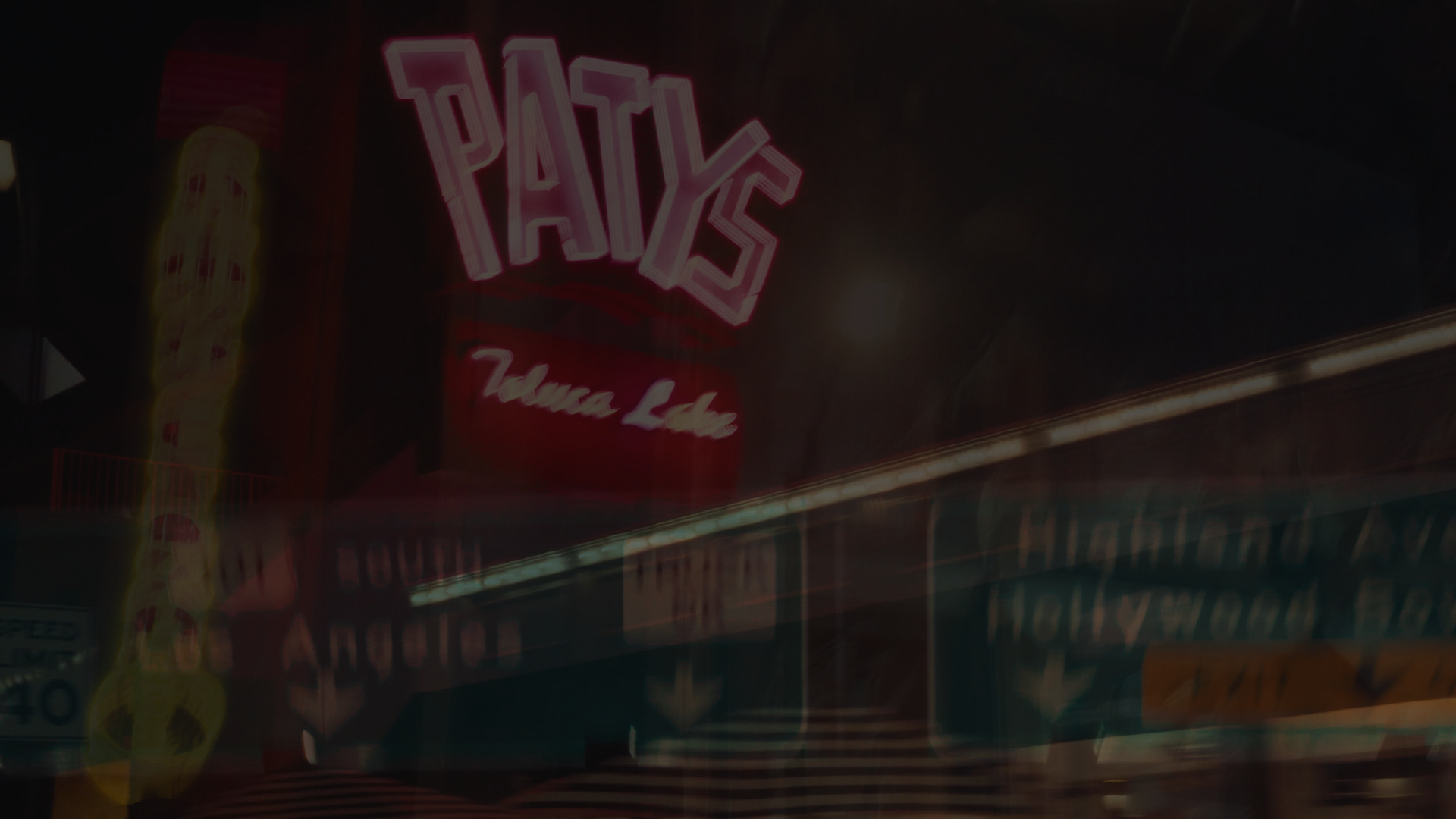 Nighttime scene of neon signs, including a pink neon sign that reads 'PAY,' and another sign below that says 'Tijuana Lounge'.