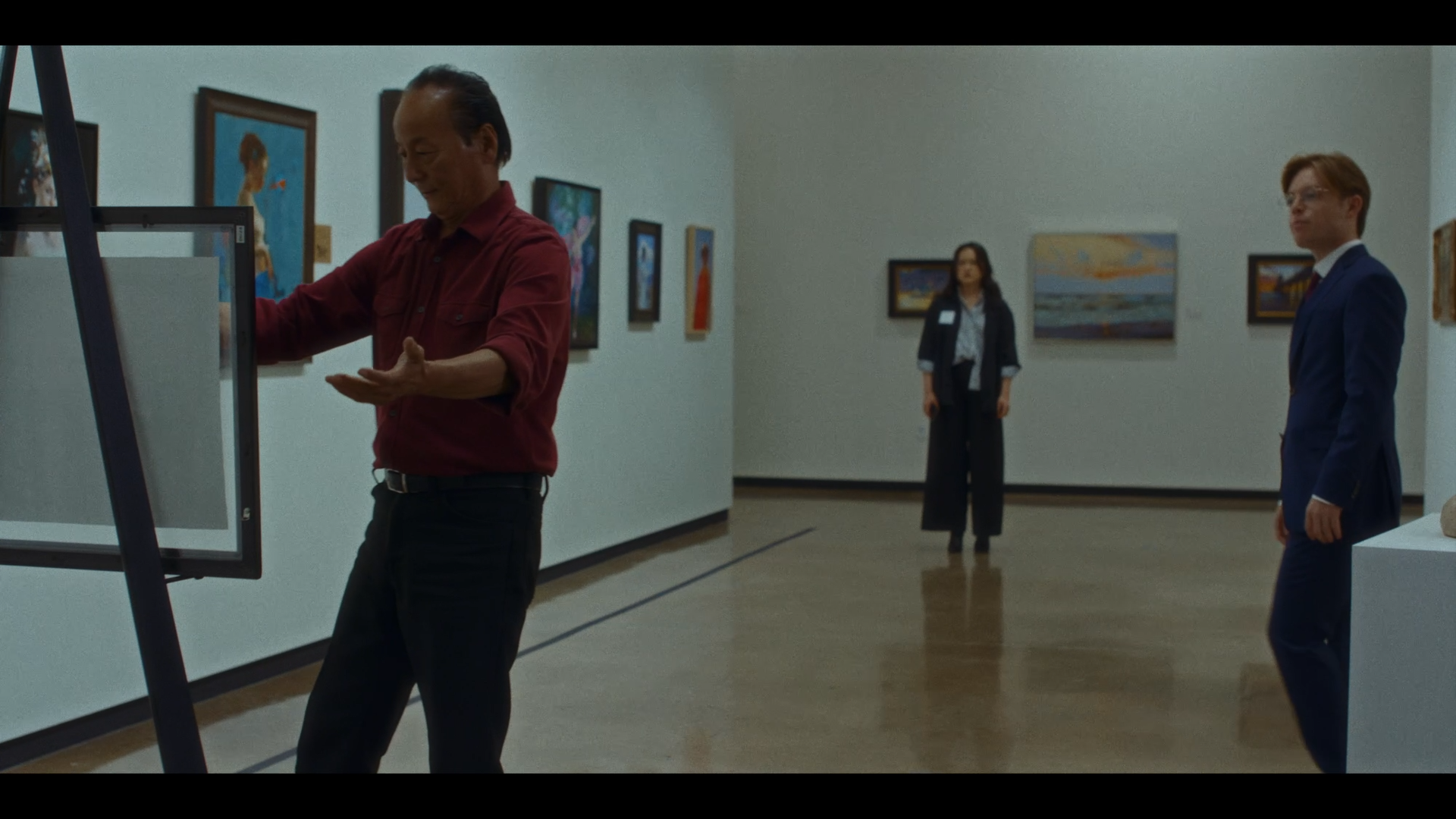 People in an art gallery viewing paintings on the wall.