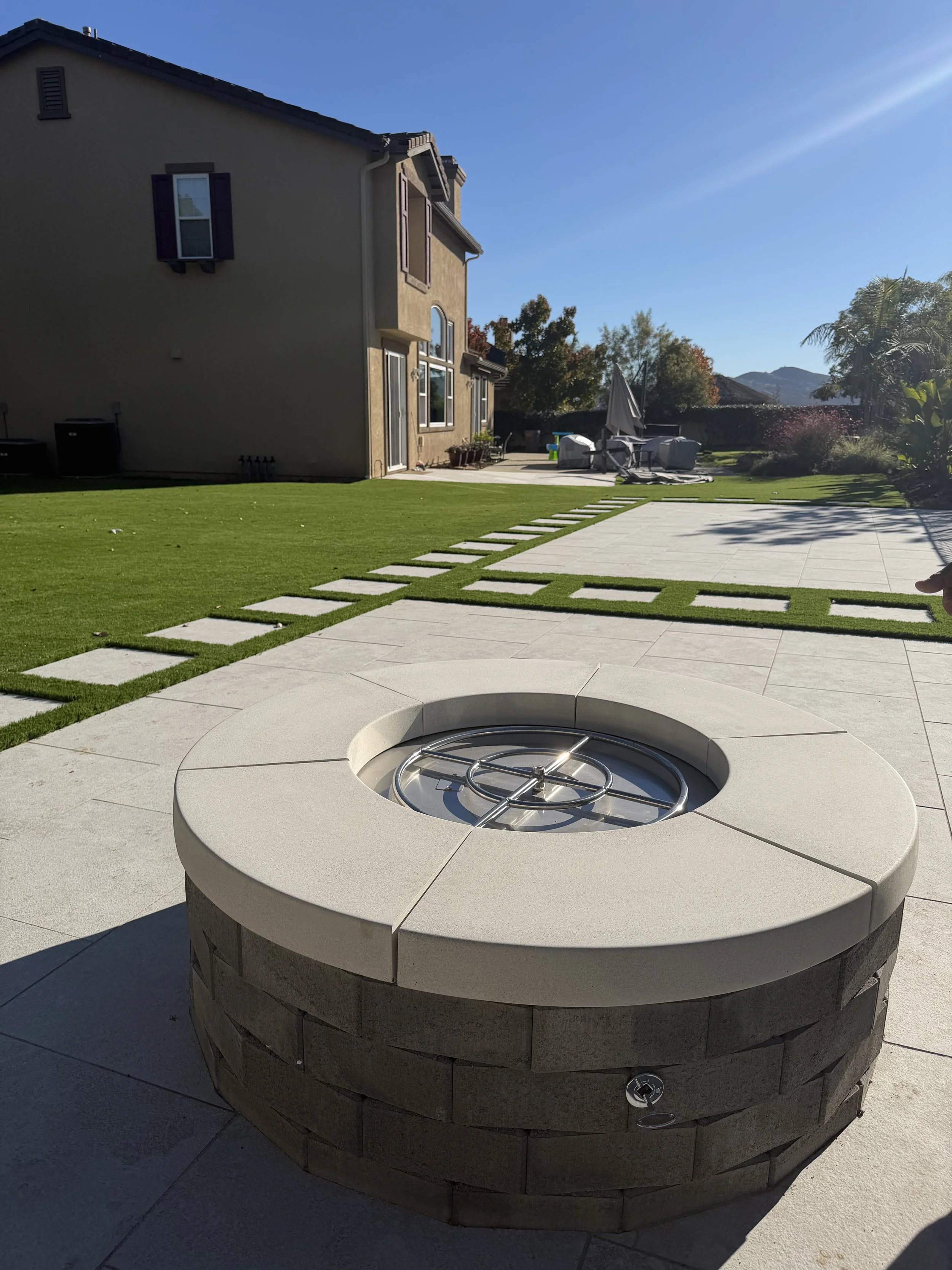 Backyard transformation including Porcelain pavers, fire pit, and artificial turf in San Marcos CA