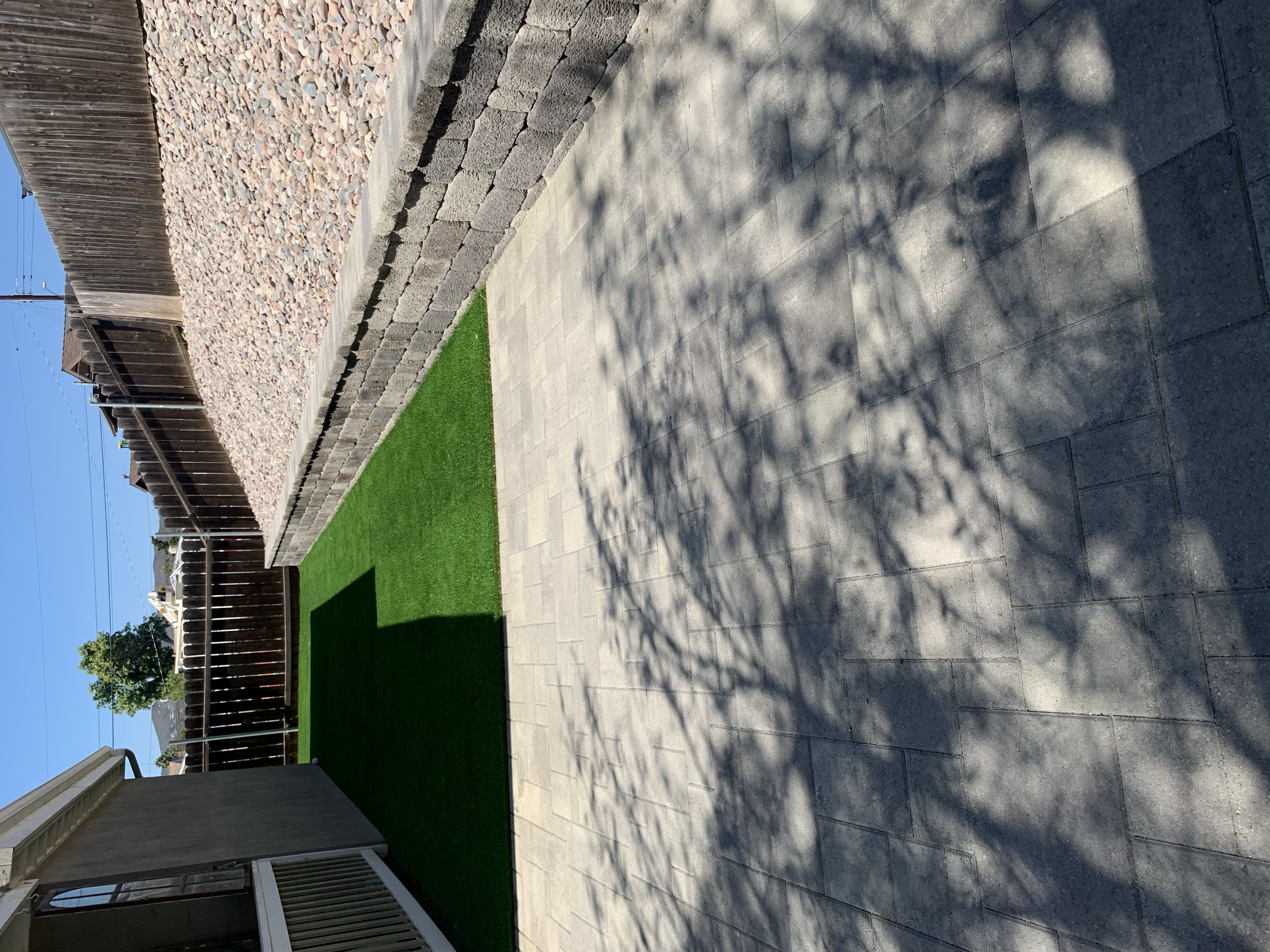 Complete backyard upgrade featuring pavers, artificial turf, decorative rock, and a custom retaining wall for a clean, low maintenance finished space.