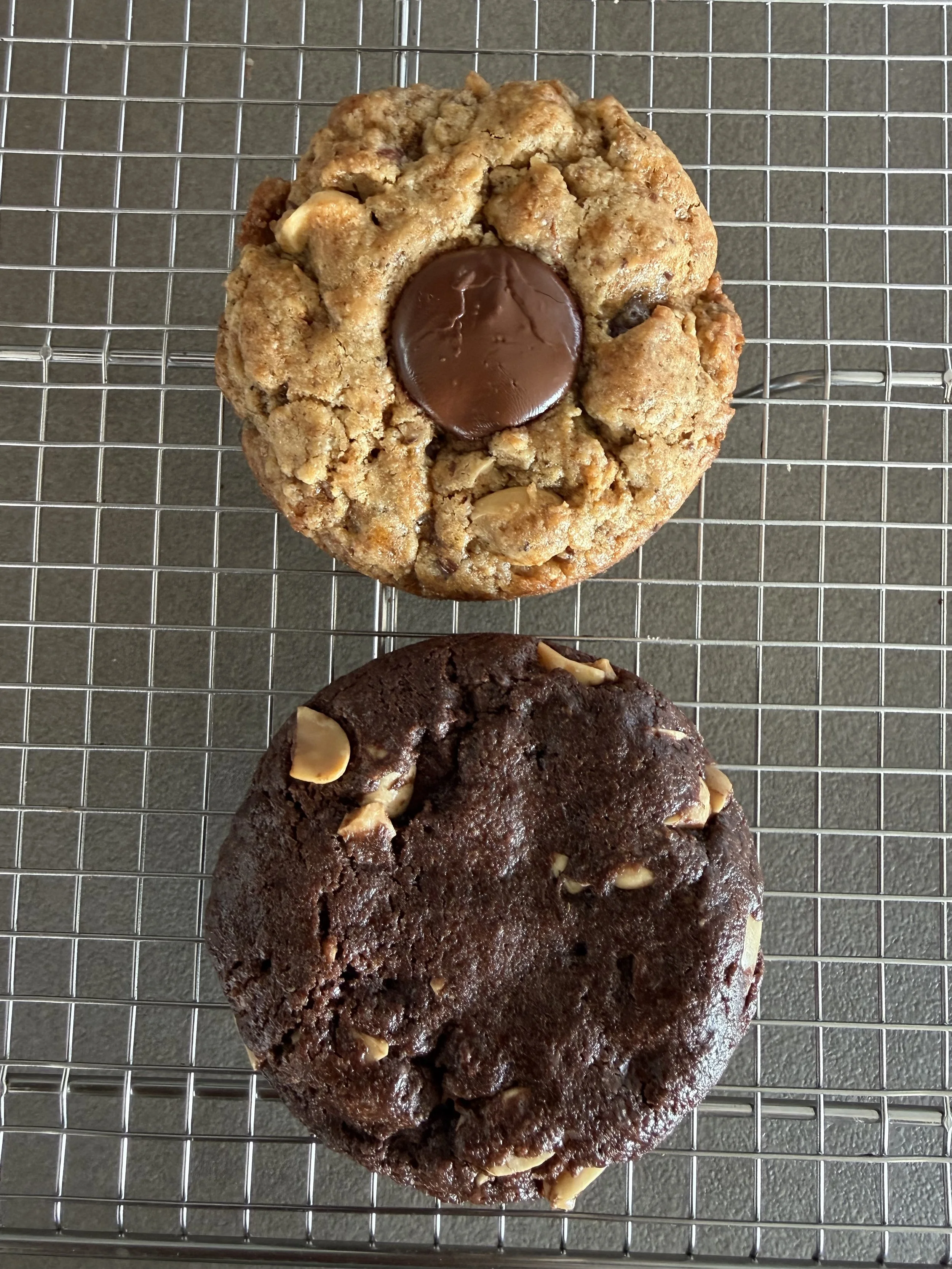 クッキー2枚、上はナッツ入りのクッキー、中央にチョコレート入りのクッキー。下はチョコレートクッキー、刻んだナッツが見える。すべて金網の上に置かれている。