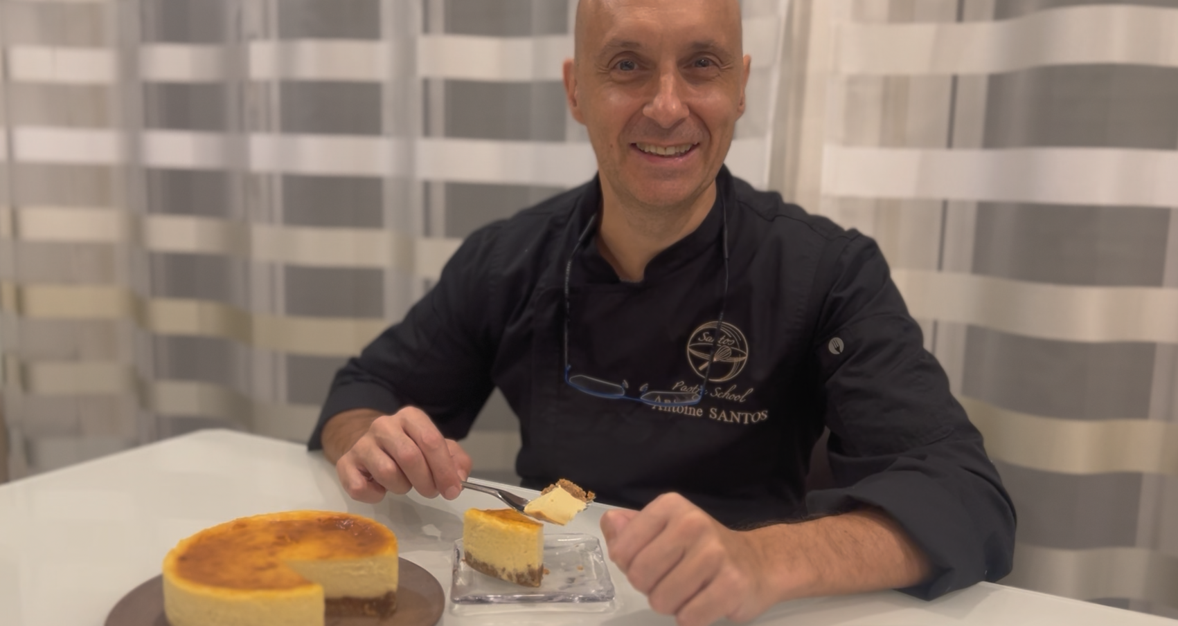笑顔の男性がテーブルでチーズケーキを食べている写真