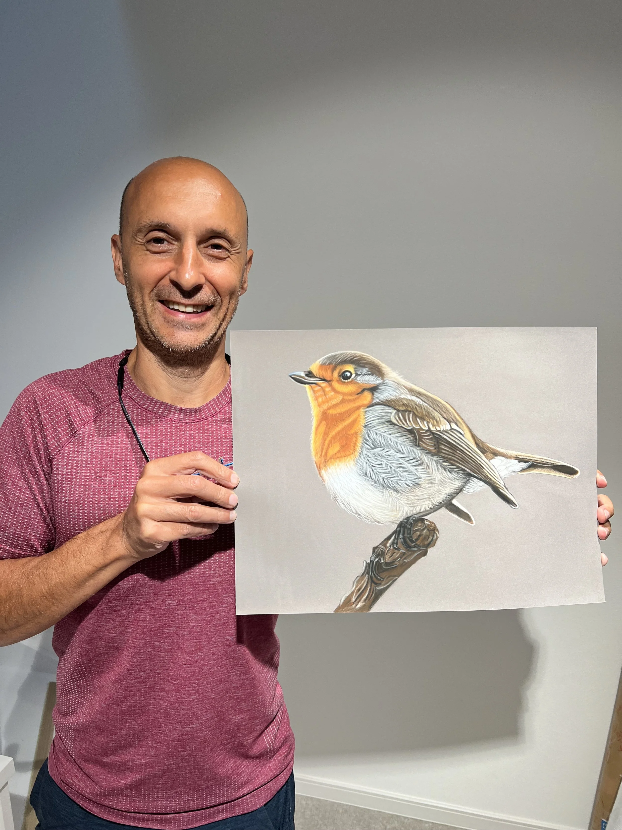 笑顔の男性が鳥の絵の横に立っている写真