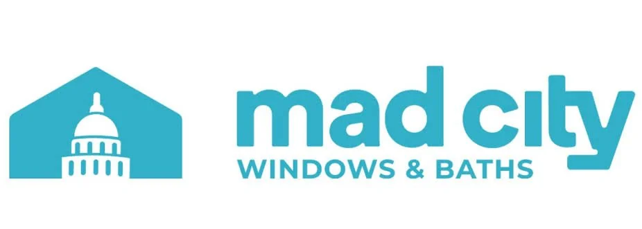 Logo for Mad City Windows & Baths featuring a stylized blue house with a dome on top resembling a government building, and the text 'mad city WINDOWS & BATHS' in blue.
