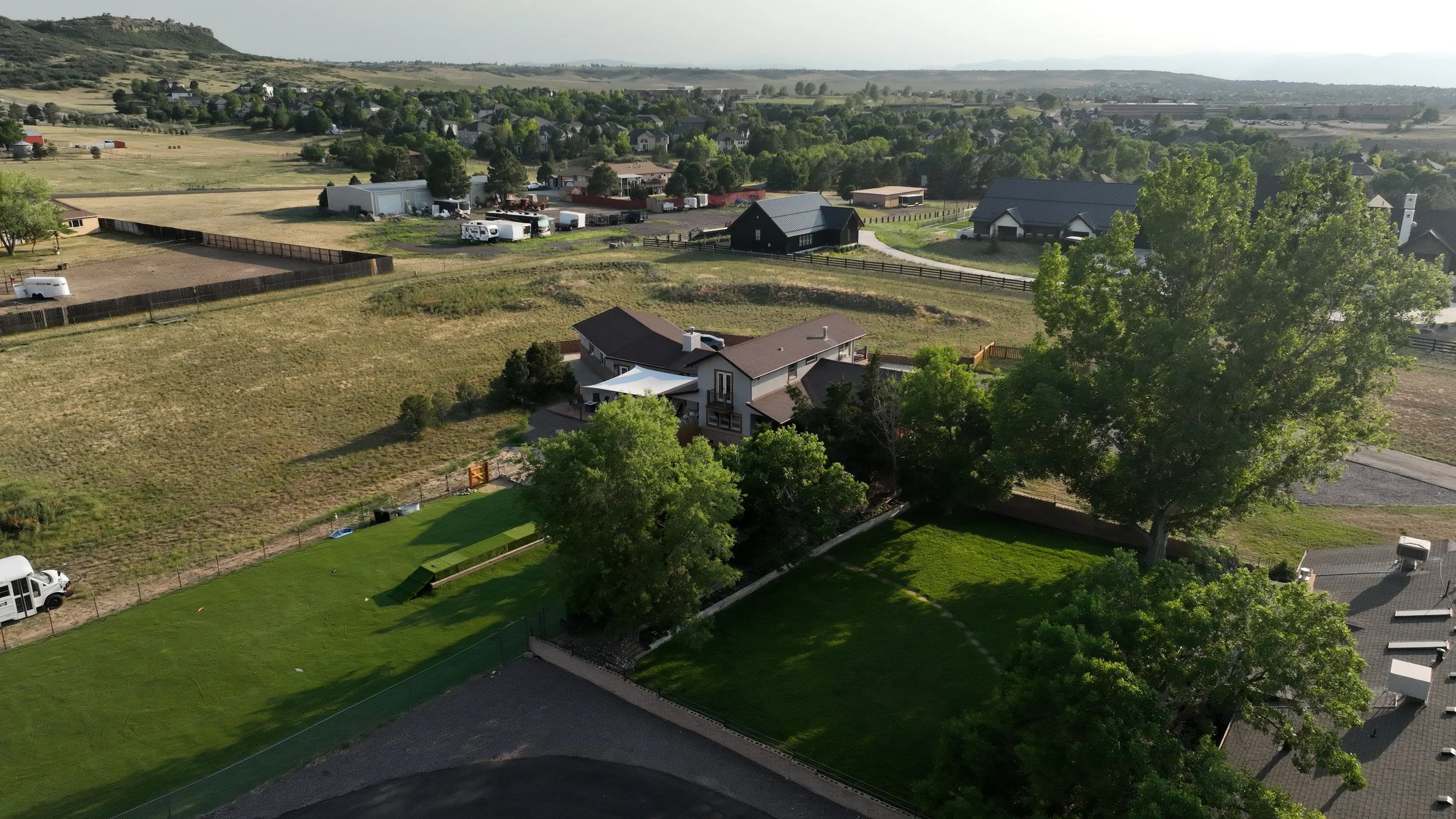 Aerial view of a suburban neighborhood with houses, trees, and open land.