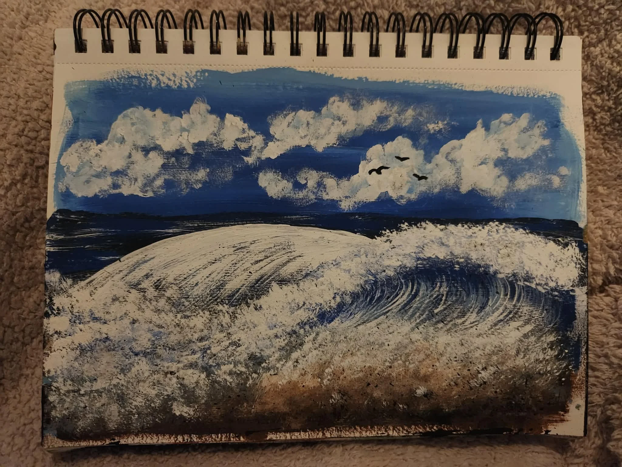 Original painting. A painted landscape depicting a blue sky with numerous white clouds and a few birds flying, with a body of water and dark land or rocks at the bottom.