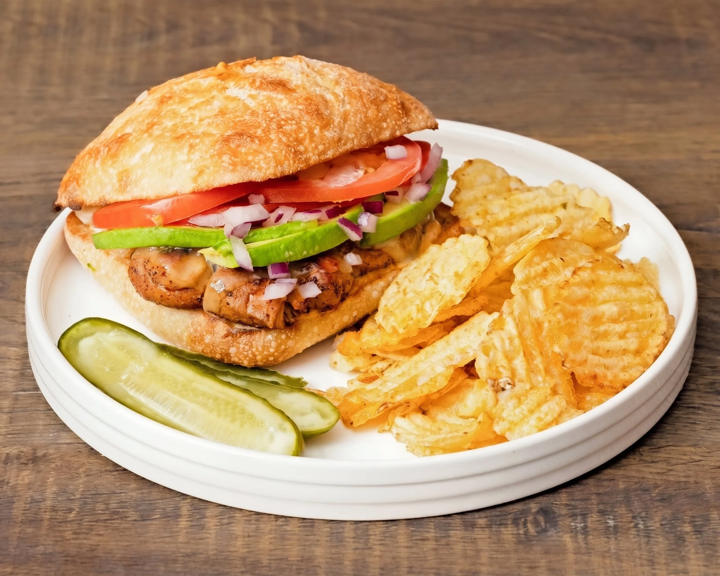 Tom Brady grilled chicken sandwich with avocado, tomato, red onion, chips, and pickle