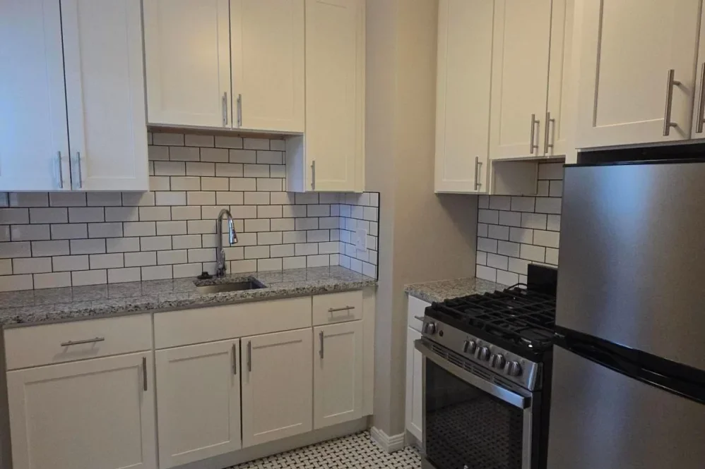 Kitchen with white cabinets, granite countertops, white subway tile backsplash, stainless steel refrigerator, oven, and sink