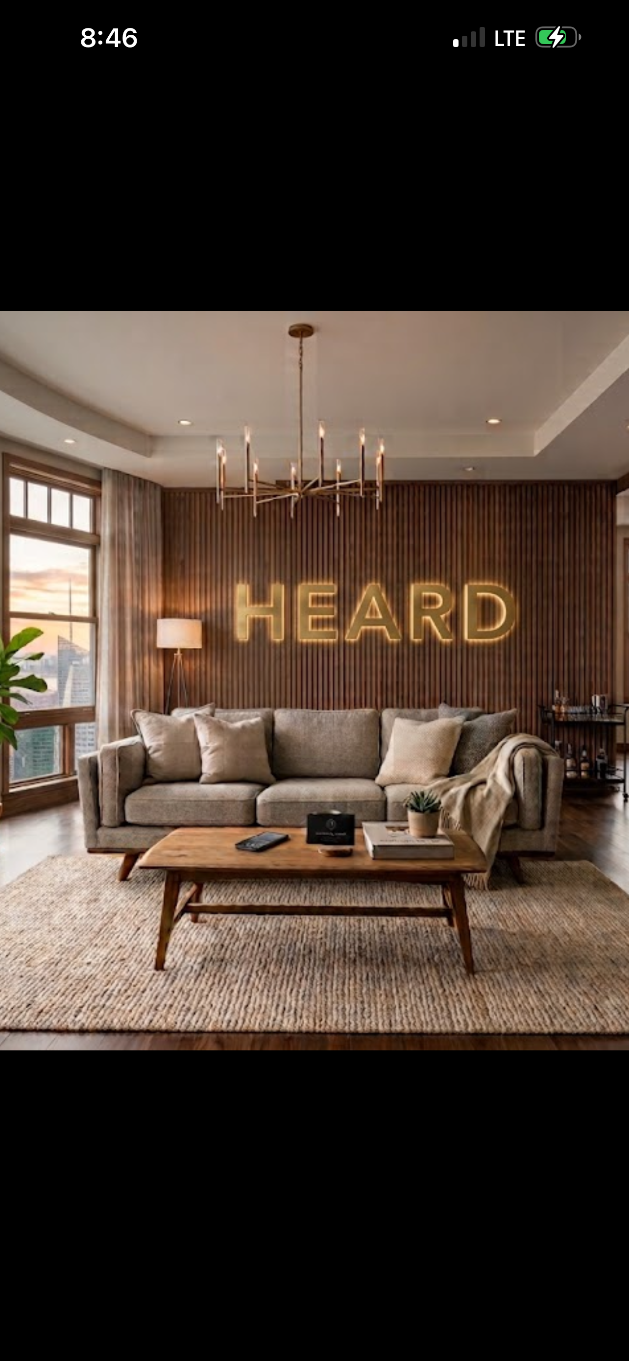 Modern living room with illuminated HEARD sign, sofa, coffee table and plants.