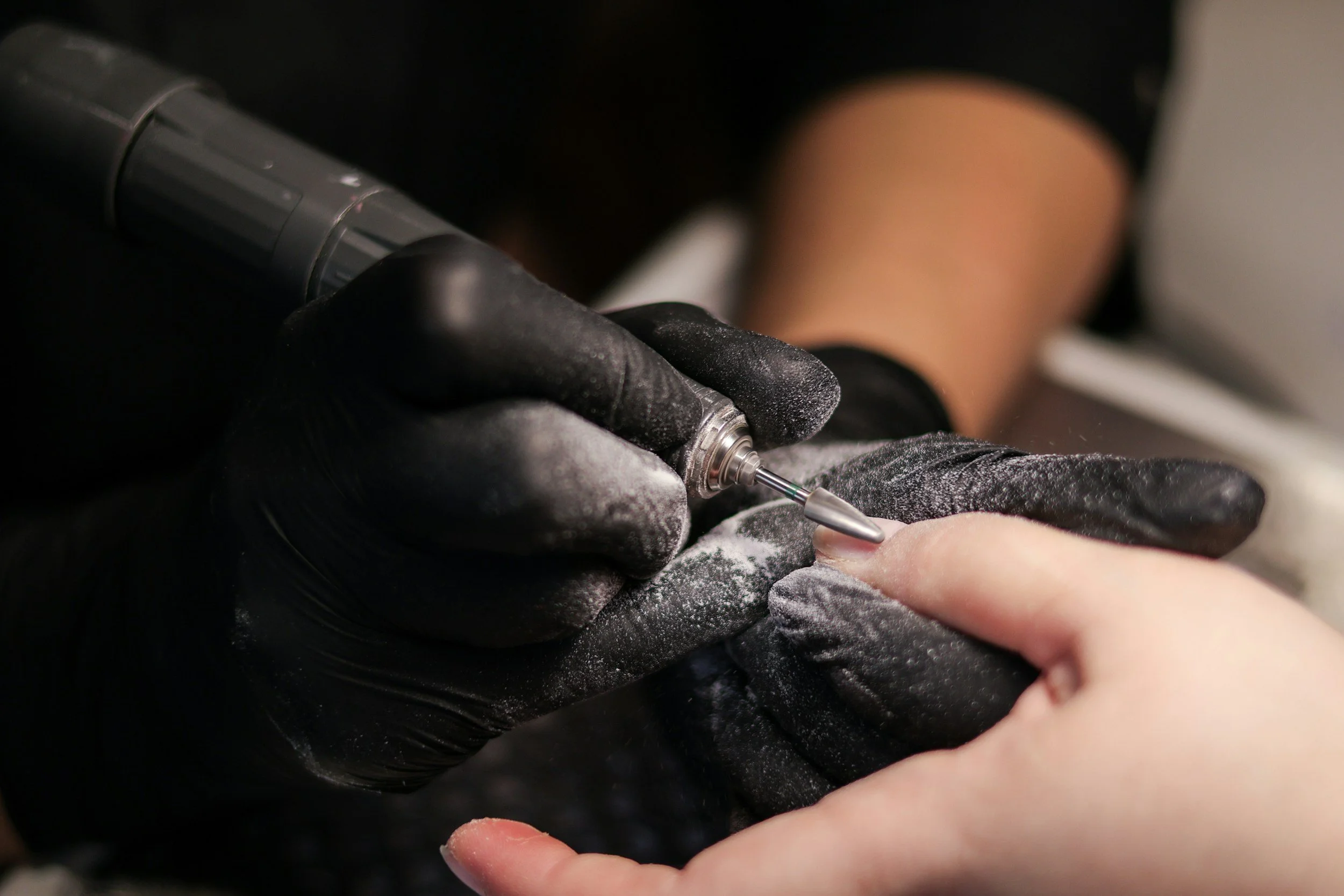 Close-up of a person receiving a tattoo from a tattoo artist using a tattoo machine, with the artist wearing black gloves.