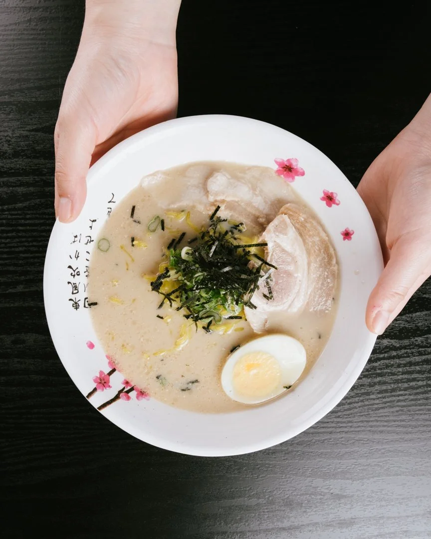 Bowl of Tonkotsu ramen with sliced pork, soft boiled egg, green onions, and seaweed.