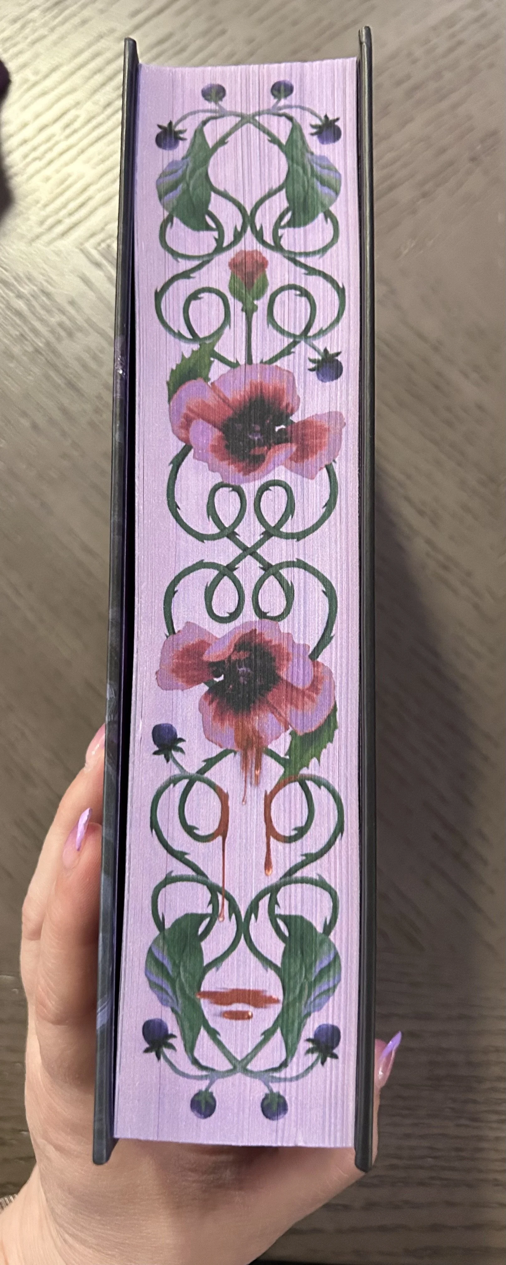 Lavender illustrated page edges featuring poisonous flowers, curling green vines, drops of blood and a small pair of lips.