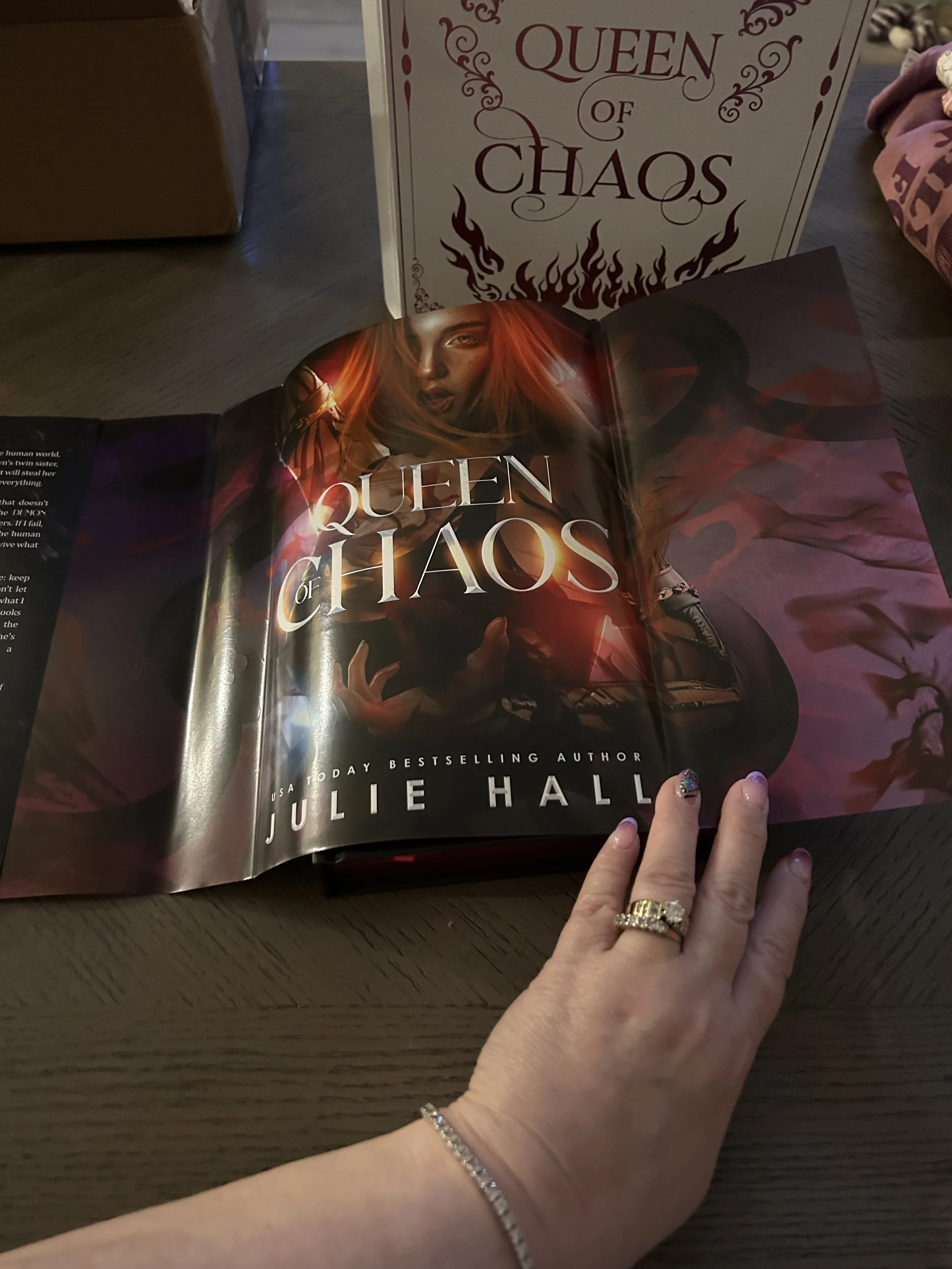 Reverse side of the Queen of Chaos dust jacket featuring full-cover fantasy artwork of an orange-haired woman against a dark pink background.