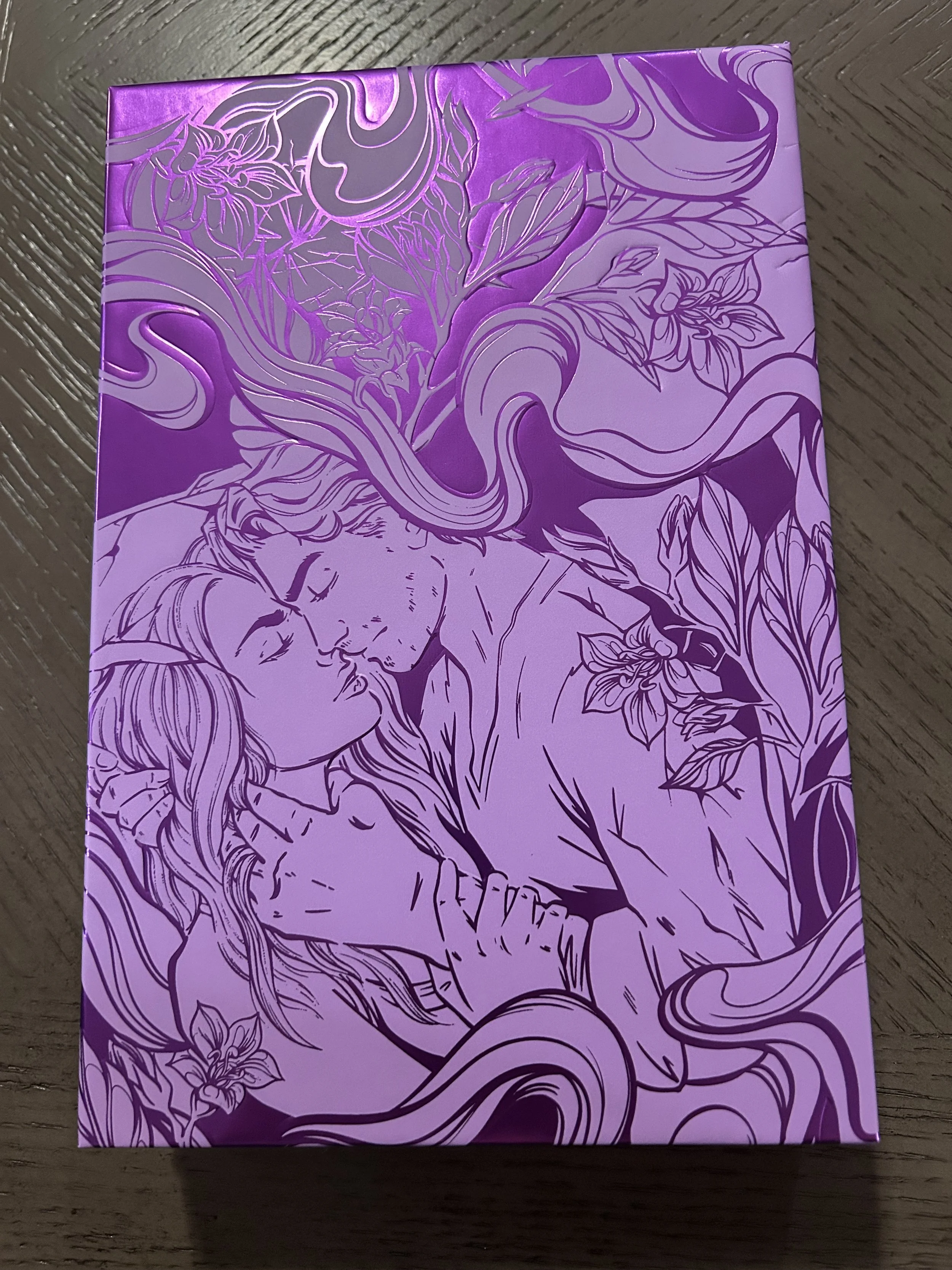 Metallic-purple illustrated slipcase featuring a couple surrounded by flowers and swirling botanical designs.