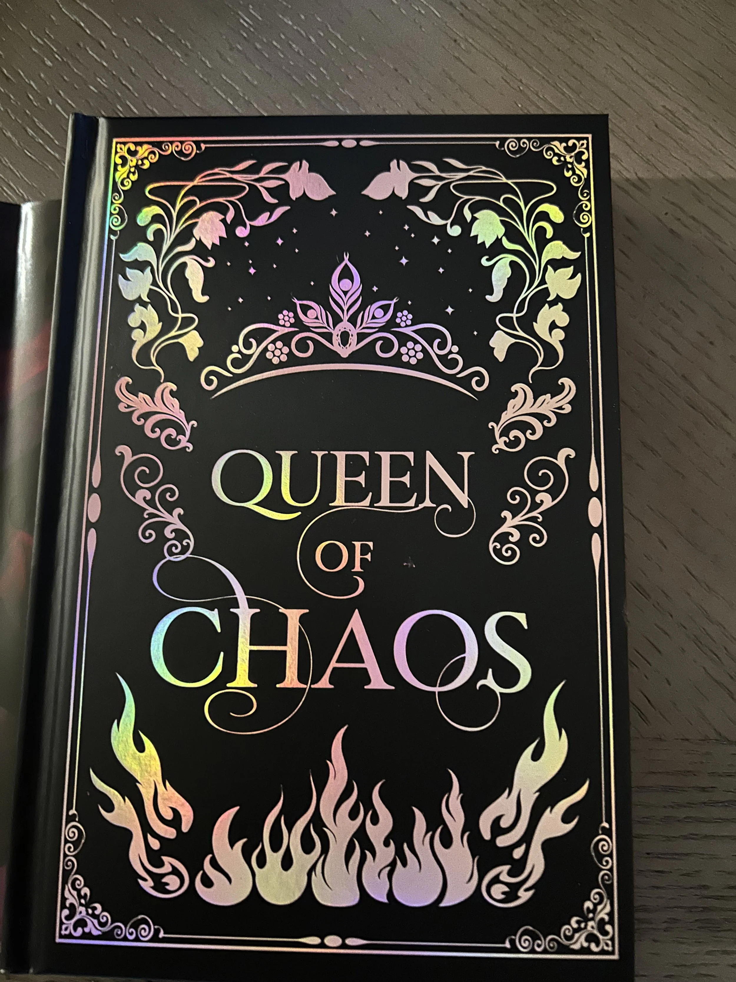 Black Queen of Chaos hardcover decorated with iridescent foil vines, a crown and pink flames.